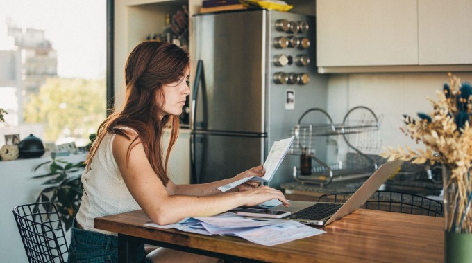 Mujer revisando papeles y en su computador