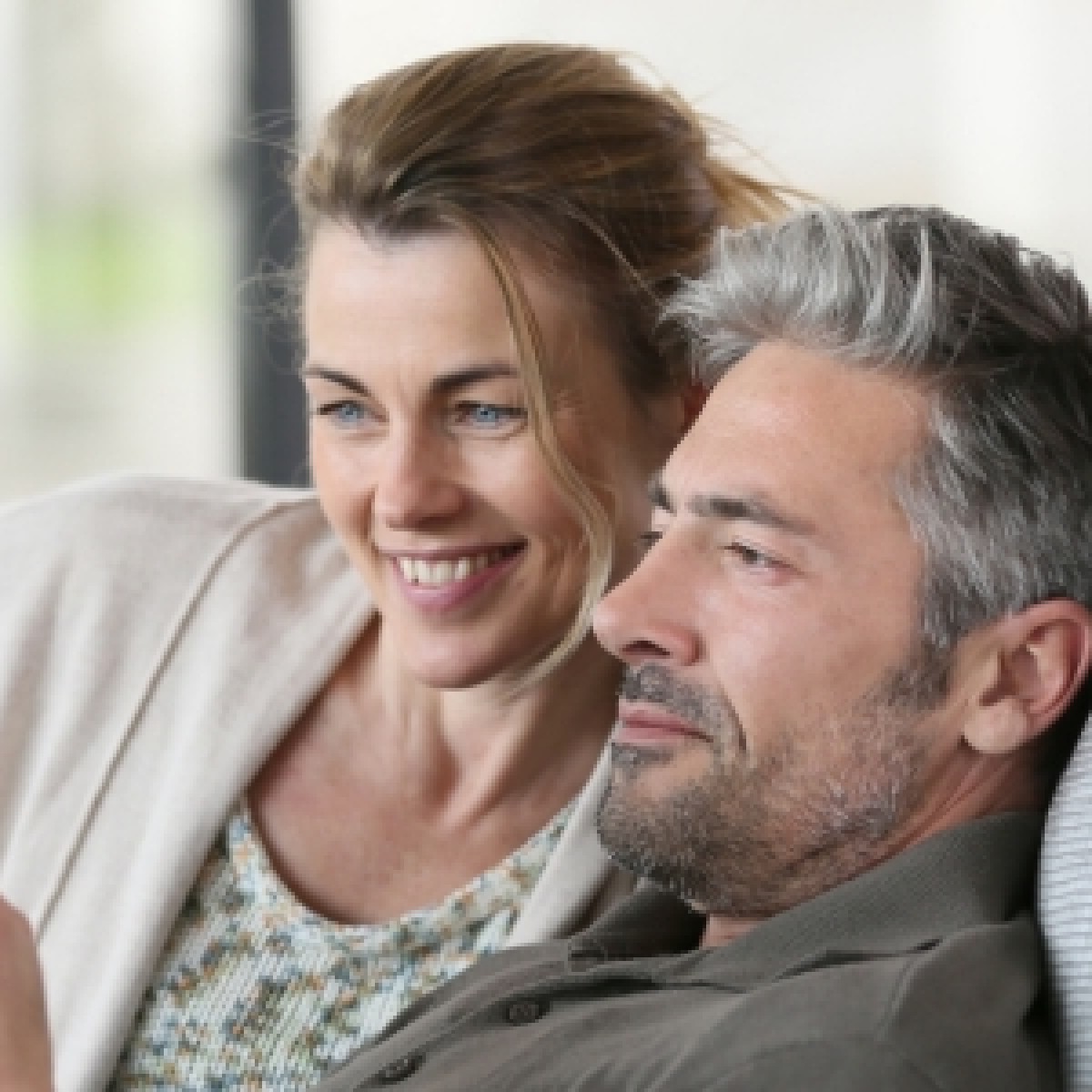 pareja de adultos sentados en el sofa leyendo en un ipad